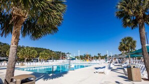 Zona de piscina con sillas de descanso y palmeras.