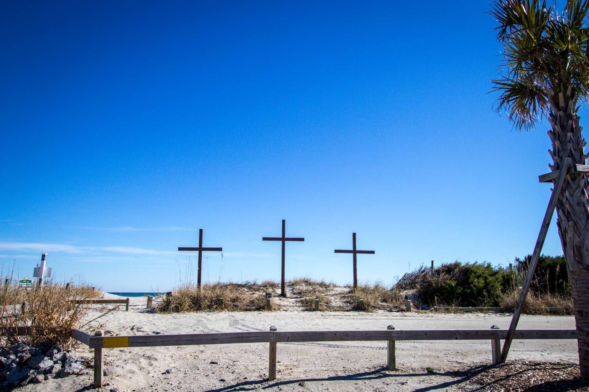 Une scène de plage avec trois croix et une clôture en bois.