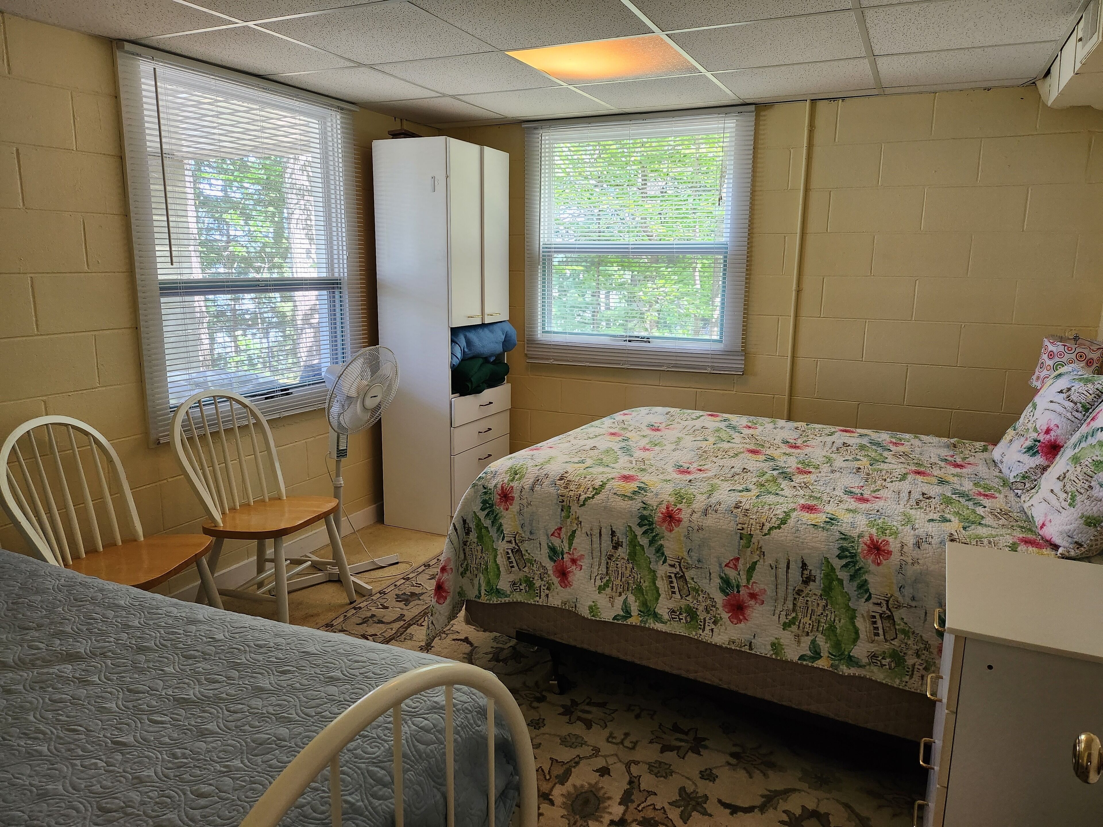 A bedroom with a bed, a desk, a chair, a wardrobe, and a TV.