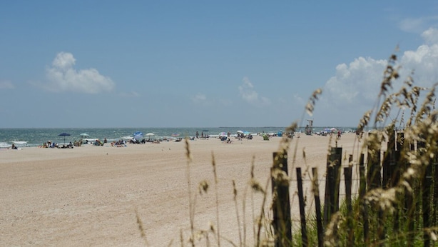 Une plage avec des gens, des parasols et une tour de surveillance des sauveteurs.