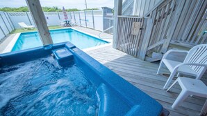A hot tub on a wooden deck with a pool in the background. - Fun 'N Sun - Nags Head MP 16, 250 Ft to Beach Access, Pool, Pets OK, YR Flex Stays (Nags Head)