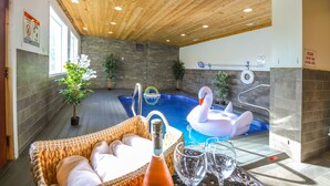 A pool area with a wooden ceiling, a swan float, and a wicker chair with cushions. - Saltwater Pool & Mtn-View Deck: Pigeon Forge Cabin (Sevierville)