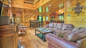 A wooden cabin interior with a dining area, kitchen, and a staircase leading to an upper level. - Saltwater Pool & Mtn-View Deck: Pigeon Forge Cabin (Sevierville)
