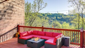 A wooden deck with a red railing, a sectional sofa with red cushions, and a glass-top fire pit. - Saltwater Pool & Mtn-View Deck: Pigeon Forge Cabin (Sevierville)