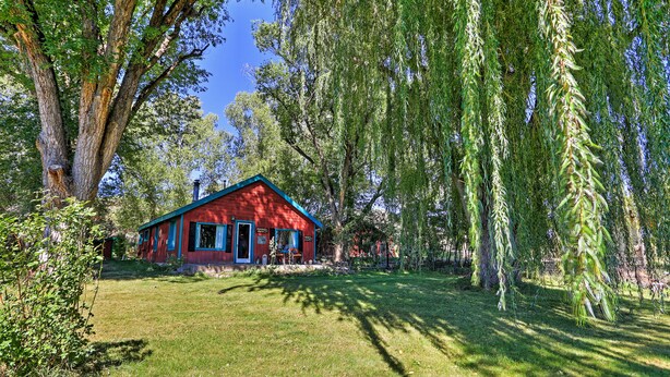 A red building with a blue roof, surrounded by lush greenery and trees. - Quiet Durango Farmhouse w/ Beautiful Yard & Gazebo (Durango)