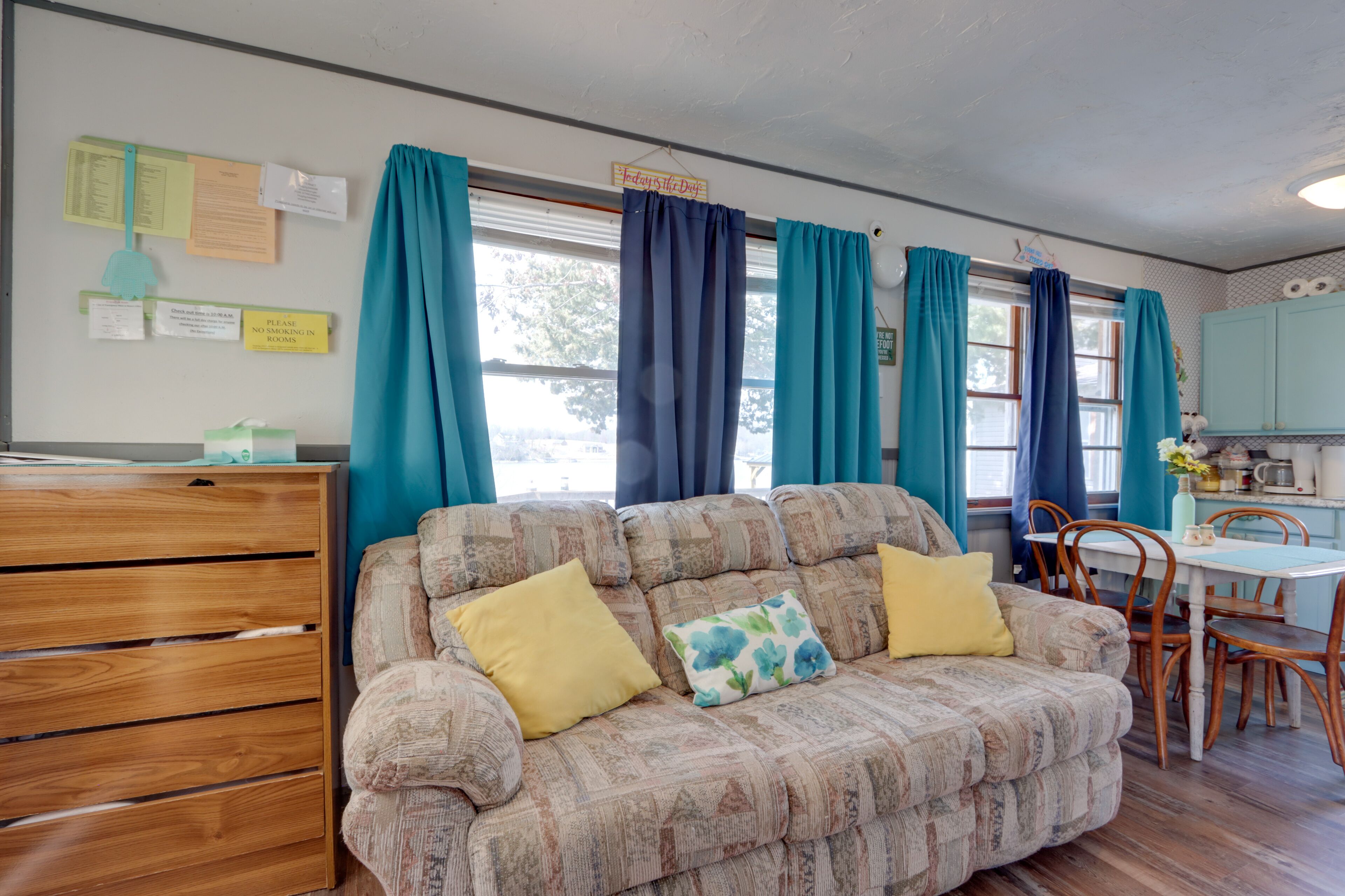 A cozy living room with a sofa, wooden dresser, and a dining area with a table and chairs.