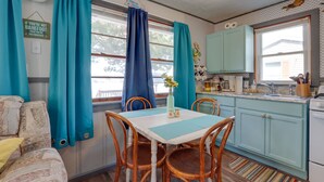 Una cocina acogedora con armarios azul verdosos, una mesa de comedor con sillas y una ventana con cortinas.