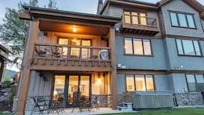 A two-story house with a balcony, outdoor seating, and a covered patio area.