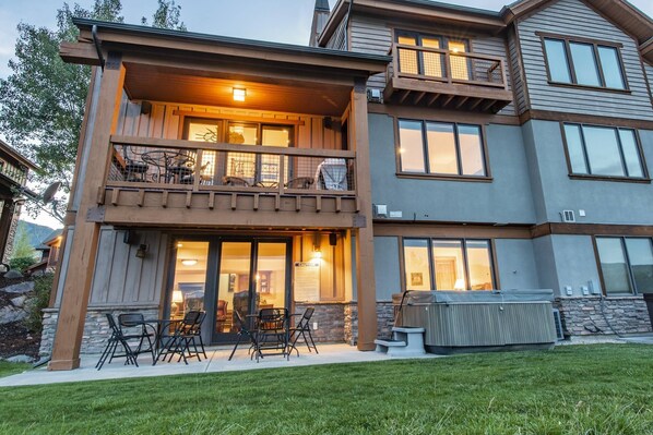 A two-story house with a balcony, outdoor seating, and a covered patio area.