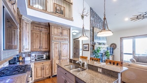 A spacious kitchen with granite countertops, wooden cabinets, and a central island with a sink.