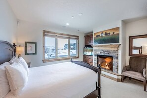 Un dormitorio con una cama grande, una chimenea, un ventanal y vistas al exterior.