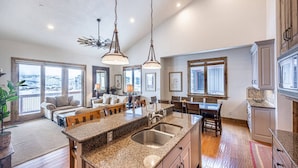 A spacious kitchen with granite countertops, a central island, and pendant lighting.