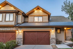 A two-story house with a garage, stone foundation, and a sloped roof. - Deer Valley East Stillwater | 9922 Vista (Heber City)