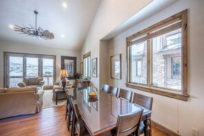 A spacious dining area with a large wooden table and chairs, large windows with views, and a modern ceiling fan. - Deer Valley East Stillwater | 9922 Vista (Heber City)