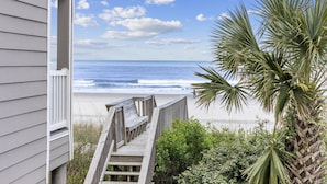 A wooden deck leading to a beach with ocean views, a palm tree, and a building with white siding. - *Fall into Savings-20% Off New Bookings thru 2026* (Surfside Beach)