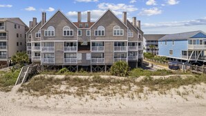 A beachfront multi-story building with balconies, a sandy foreground, and a clear sky. - *Fall into Savings-20% Off New Bookings thru 2026* (Surfside Beach)