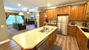 A modern kitchen with wooden cabinets, stainless steel appliances, and pendant lighting.