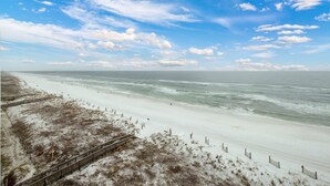 Een strand met een houten vogelbeschermingspad dat naar de kust leidt, zandduinen en een heldere lucht.