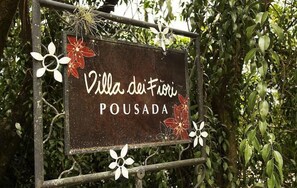 A sign for Villa dei Fiori Pousada with decorative flowers.