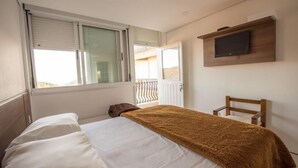 A bedroom with a bed, a TV mounted on the wall, and a window with blinds. - Pousada Villa Dei Fiori (Bento Gonçalves)