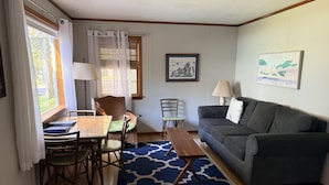 A living room with a wooden table, two chairs, a sofa, a blue patterned rug, and two lamps. - Cozy cottage Big Glen Lake, Tennis Court, Dock, Kayaks, Rowboat, Sunset view (Maple City)
