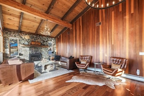 A cozy living room with a stone fireplace, leather furniture, and a wooden ceiling.
