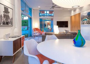 A modern interior with a dining area, a sofa, and a large window.