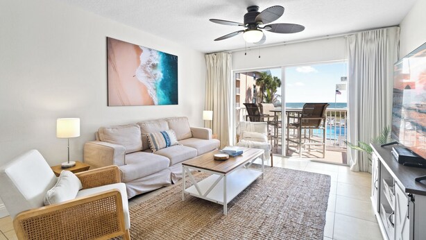 Una habitación de hotel moderna con balcón, un sofá, una mesa de centro y un televisor.