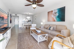 A modern living room with a sofa, coffee table, and a dining area with chairs.