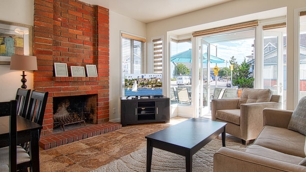 A living room with a brick fireplace, a television on a wooden stand, a sofa, and a coffee table. - Awesome lower unit in a duplex just one house away from the sand and boardwalk! (Newport Beach)
