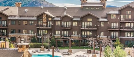 Un hotel de varios pisos con piscina, zona de estar al aire libre y vistas a la montaña.