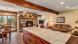 A spacious living area with a stone fireplace, wooden beams, a large marble island, and a cozy couch. - Perfect for Biking/Hiking/Skiing! Hot tub access, Walk to Main Street, Covered p (Breckenridge)