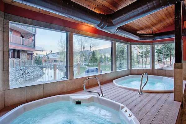 A spa area with two hot tubs and a view of a mountain landscape.