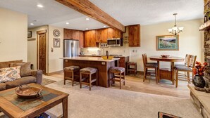 A spacious living area with a wooden dining table and chairs, a kitchen with wooden cabinets and stainless steel appliances, and a cozy seating area with a sofa and coffee table. - Perfect for Biking/Hiking/Skiing! Hot tub access, Walk to Main Street, Covered p (Breckenridge)