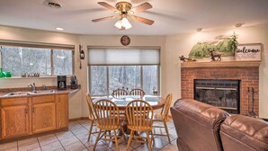A kitchen with wooden cabinets, a dining table with chairs, a fireplace, and a ceiling fan. - Pet-Friendly Apt w/ Views in Pisgah Nat’l Forest! (Burnsville)