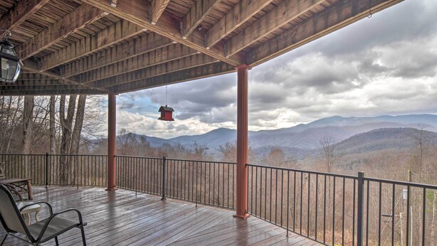 A wooden deck with a metal railing, two chairs, and a hanging lantern. - Pet-Friendly Apt w/ Views in Pisgah Nat’l Forest! (Burnsville)