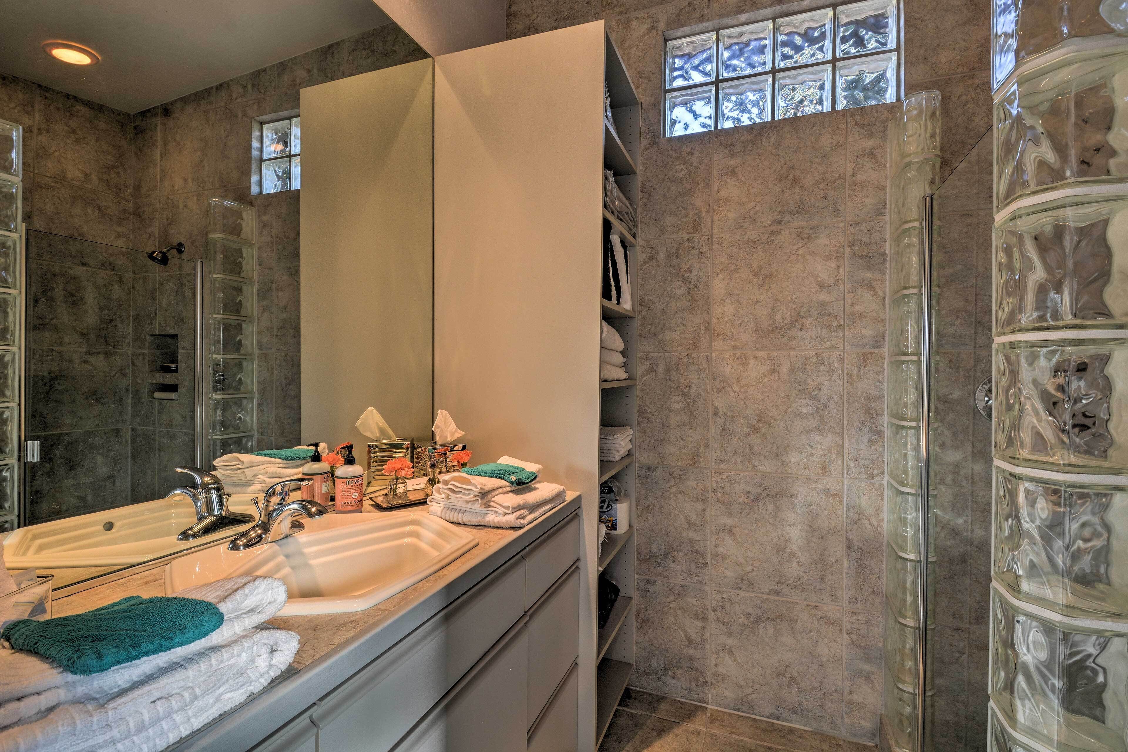 A bathroom with a large mirror, two sinks, and a glass shower enclosure.