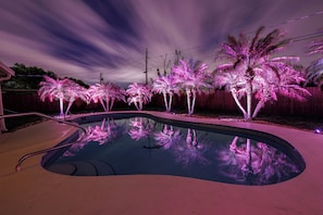A swimming pool with a wooden deck and a fence in the background.