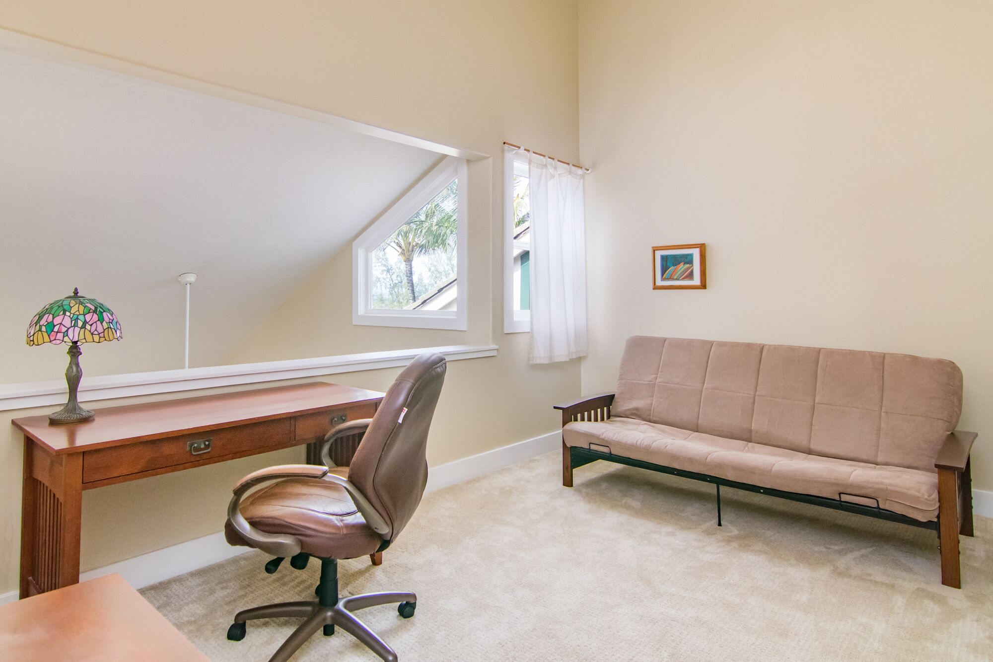 Ein Zimmer mit Schreibtisch, Stuhl und Sofa.