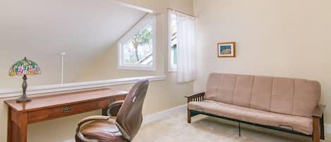 Ein Zimmer mit Schreibtisch, Stuhl und Sofa.
