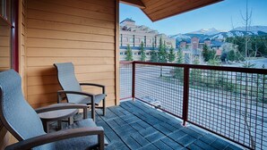 Un balcon avec deux chaises et une vue sur un complexe hôtelier et des montagnes.