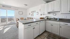 A kitchen with white cabinets, a countertop, and a view of the ocean through a sliding door. - Cozy 3 bedroom, 1.5 bathroom condo located on on 122nd Street and oceanfront (Ocean City)