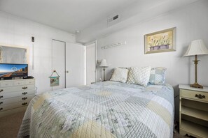 Ein Schlafzimmer mit Bett, Kommode, Fernseher und Bildern an der Wand.