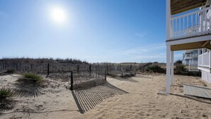 A beach house with a wooden deck, a fenced area, and a clear sky. - Cozy 3 bedroom, 1.5 bathroom condo located on on 122nd Street and oceanfront (Ocean City)
