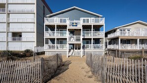 A beachfront hotel with multiple balconies, a sandy walkway, and a clear blue sky. - Cozy 3 bedroom, 1.5 bathroom condo located on on 122nd Street and oceanfront (Ocean City)