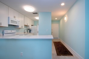 Compact kitchen area with a microwave, stove, sink, and refrigerator.