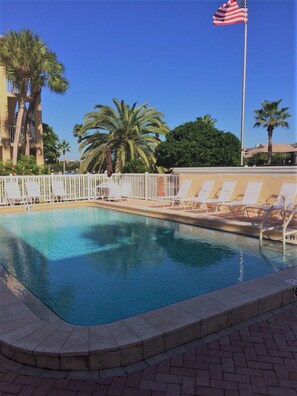 Relax by the pool surrounded by lush greenery and lounge chairs.