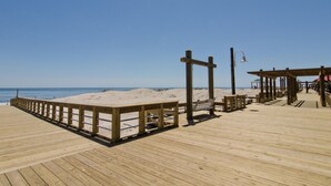 Une jetée en bois, dotée de bancs et d’un kiosque, qui offre une vue sur une plage de sable.