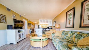 Un espacio habitable compacto con cocina, comedor y sofá estampado con motivos tropicales.