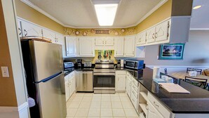 Una cocina con armarios blancos, electrodomésticos de acero inoxidable y un letrero en la pared que dice 'Beach House'.